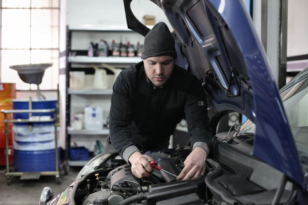 Illustrative mechanic working on a blue everyday car in a workshop